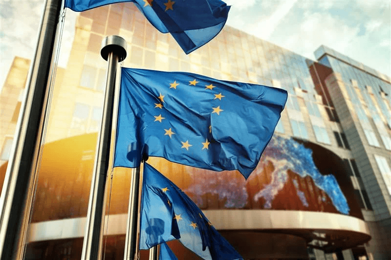 Mehrere Flaggen der Europäischen Union vor einem institutionellen Hintergrund