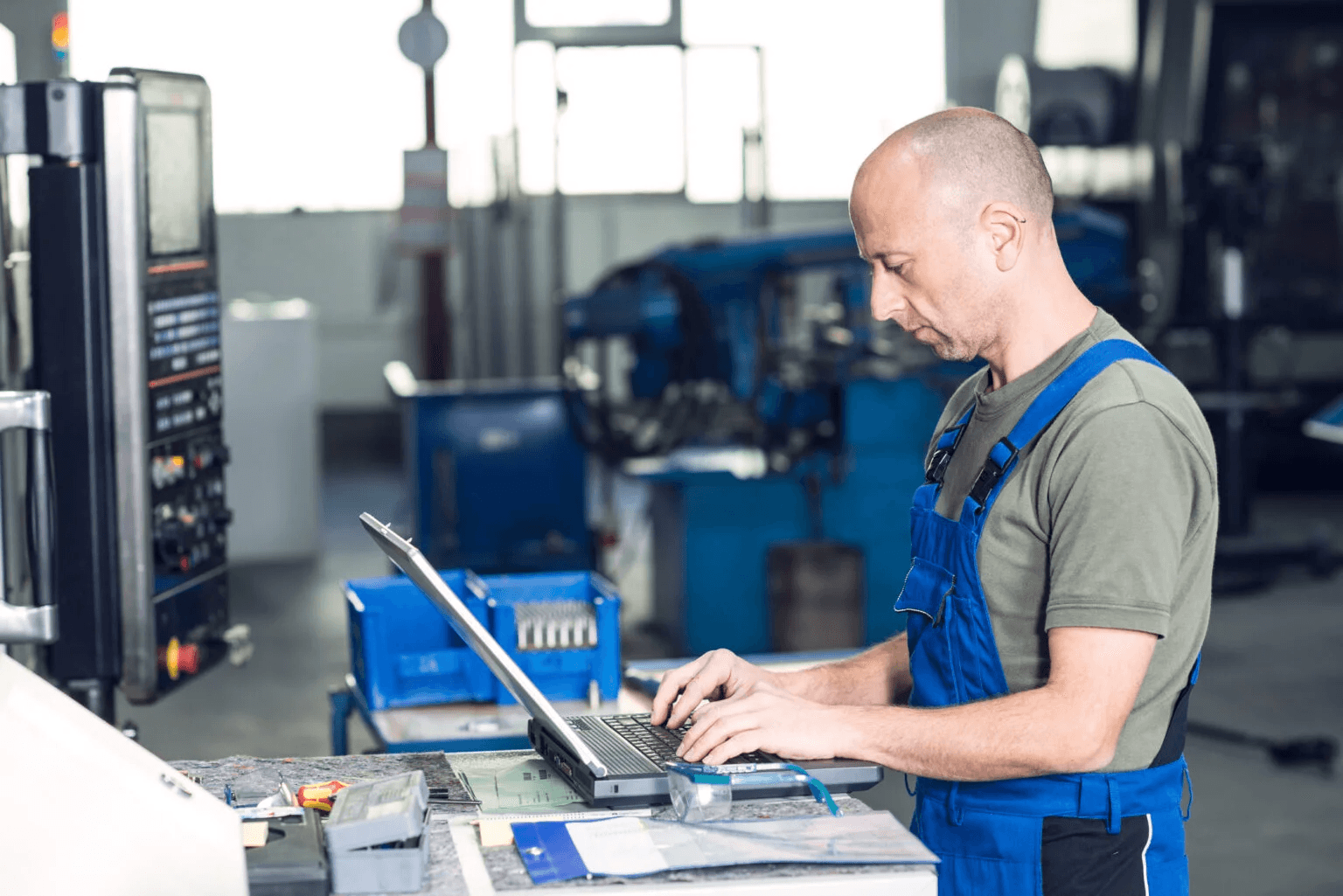 Ein Mann arbeitet mit einem Laptop in einer industriellen Fertigungsumgebung